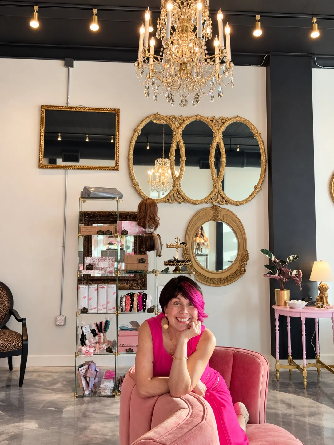 Brinn seated in a pink chair inside Coiffed